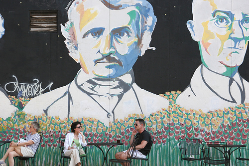 A couple talking under a huge mural two men